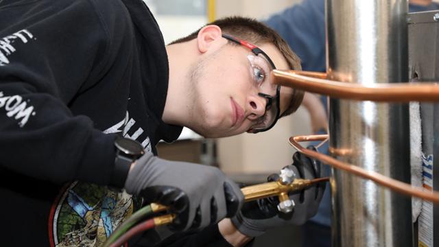 Student looking at a pipe in the H V A C lab